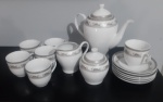 NINA STYLE- aparelho de chá composto por peças de porcelana branca com detalhes decorativos em tons de cinza prateado, formando um padrão clássico e elegante com seis xícaras com seis pires, uma leiteira, um açucareiro e um bule.Lote no estado com peças quebradas.