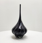 Escultura em vidro artístico de Murano  Itália, século XX. Elegante escultura em vidro de Murano, de corpo sinuoso e alongado, executada em vidro negro translúcido com inclusão de bolhas regulares e delicado efeito espiralado. O trabalho revela a maestria dos mestres vidreiros de Murano, que, por meio do sopro livre e modelagem a quente, obtêm formas fluidas e equilíbrio entre peso, transparência e movimento. O design contemporâneo e a pureza da execução refletem a tradição artesanal veneziana reinterpretada ao longo do século XX. Dimensões aproximadas: 40 x 20 centímetros.