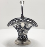 Cestinha WMF em metal prateado (marcação I/O) e vidro liso, Alemanha, circa 1900Elegante cestinha de mesa com alça móvel, manufaturada pela prestigiada WMF  Württembergische Metallwarenfabrik, tradicional casa alemã fundada em 1853 e referência mundial em metalaria artística. A peça apresenta estrutura vazada e rendilhada em metal prateado de alta qualidade (marca WMF, punção I/O), com rica decoração de grinaldas florais, volutas e medalhões lisos, típicos do estilo Jugendstil (Art Nouveau).A alça móvel, finamente trabalhada com recortes e ornamentos simétricos, complementa a harmonia e leveza do desenho. O recipiente interno em vidro liso e incolor, de formato ajustado ao corpo metálico, acompanha o contorno sinuoso da peça. O vidro apresenta antiga quebra colada, reparo estável e funcional, sem comprometer a integridade visual ou estrutural do conjunto. O punção WMF acompanhado da sigla I/O identifica a prata de qualidade superior utilizada no revestimento metálico e situa a produção no período final do século XIX a início do XX, fase de maior prestígio e exportação da manufatura. Utilizada originalmente como porta-confeitos ou cestinha de sobremesa, a peça é representativa da delicadeza e do refinamento da mesa europeia da Belle Époque, combinando arte utilitária e ornamentação de grande elegância.Dimensões:26 x 18 x 16 centímetros. Estado: Recipientede vidro quebrado e colado.