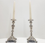 Par de castiçais em prata brasileira, D.G.B., 10 dinheiros 833,3 mls. sec. XIX. Elegantes castiçais executados em prata de lei brasileira, com fuste balustiforme e base circular quadripé, apoiada sobre pés em garra e bola, decorados com folhas e volutas em relevo. O desenho segue o estilo neoclássico / georgiano, muito presente na prataria brasileira do início do século XX. Punções gravados DGB (ourives ou manufatura) característicos da produção nacional do período. Dimensões: 23x13 centímetros. Peso: 656 gramas.