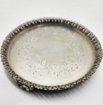 Salva em prata brasileira, marca I.G., teor 835, meados do século XX. Salva circular em prata de lei com borda recortada e rendilhada, apoiada sobre três pés ornados por folhas de acanto. Centro gravado com decoração floral e arabescos de fino traço. Punções PRATA, IG e 835 gravados na base, correspondentes à oficina brasileira ativa na metade do século XX. Diâmetro:14 centímetros. Peso: 189 gramas.