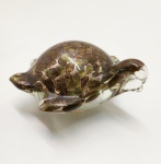 Delicada escultura zoomórfica em vidro artístico de Murano, modelada à mão na forma de tartaruga. Peça de corpo translúcido com inclusões metálicas em tons dourados e acobreados, criando efeito iridescente sob a luz. Trabalho típico das oficinas muranesas da segunda metade do século XX, de execução fluida e equilibrada, evidenciando a técnica do sommerso com uso de aventurina (partículas cintilantes de cobre). Dimensões: 6 x 13 x 12 centímetros.