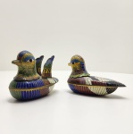 Par de caixas decorativas em forma de patos mandarins, executadas em metal dourado com esmalte cloisonné  policromado, ricamente decoradas com motivos geométricos e plumagem estilizada em tons de azul, verde, vermelho, preto e branco, sobre fundo dourado. Interior esmaltado em azul cobalto vívido. Peças finamente modeladas, representando o símbolo oriental da fidelidade e união conjugal. Dimensões: 5x7 centímetros cada.