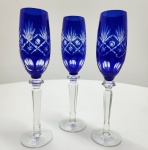 Conjunto de três elegantes taças de licor em cristal bicolor (overlay), com corpo em cristal transparente recoberto por camada azul cobalto, finamente lapidadas à mão em motivos geométricos e florais, revelando a camada inferior incolor. Hastes facetadas e bases lisas, de proporções equilibradas e brilho excepcional. Peças de tradição artesanal boêmia. dimensões: 24x6 centímetros.