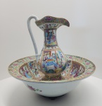 - Cia das Índias- raro e imponente conjunto de jarro e bacia em porcelana chinesa, ricamente ornamentado na paleta Famille Rose, típica do período tardio da dinastia Qing. A decoração apresenta amplas reservas figurativas com cenas cortesãs, ambientes palacianos e personagens finamente delineados, intercaladas por bordas com florões, arabescos e elementos tradicionais da estética cantonês. O jarro, de corpo faceteado e bocal ondulado, exibe narrativa contínua em esmaltes de ótima vivacidade e saturação. A bacia, de largo diâmetro, repete o mesmo programa iconográfico, formando um conjunto altamente decorativo e de grande presença visual. As bases apresentam sinais coerentes de idade, com desgaste autêntico do esmalte, reforçando a antiguidade da peça. 50 x 55 centímetros.