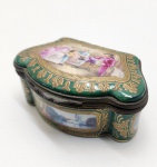 Raríssima caixa de joias em Porcelana Sèvres, França, Século XVIII (c. 1760 a 1780). Porcelana dura finamente moldada, ricamente esmaltada em tons vivos e ornamentada com douração a ouro polido, típica das produções da manufatura real no reinado de Luís XV e Luís XVI. A tampa apresenta cena galante pintada à mão, executada com pinceladas delicadas e composição equilibrada, característica dos miniaturistas de Sèvres. As laterais exibem cartelas ovais com reservas pintadas com paisagens bucólicas e arabescos neoclássicos, realçadas por enquadramento dourado em estilo rococó. Interior em esmalte branco. Na base, marca azul da manufatura: dois L entrelaçados (sinal real), acompanhados pela letra-data M, correspondente ao ano de produção dentro da cronologia oficial da fábrica. Dimensões:4x6x6 centímetros