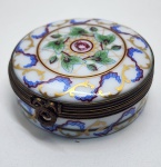 Encantadora caixa de porcelana Limoges Castel France, ricamente decorada com finos arabescos, guirlandas florais e delicados detalhes em ouro aplicados à mão. A superfície apresenta pintura refinada em tons suaves que ressaltam o brilho característico da porcelana de Limoges, enquanto o interior da tampa traz a inscrição dourada Délice de mon cur, adicionando um toque romântico e tradicional. As ferragens em bronze patinado mantêm o charme clássico das peças francesas, e a base exibe a marca Limoges Castel France acompanhada da etiqueta H. Stern, atestando procedência de alta qualidade. Dimensões: 2x 6 centímetros.