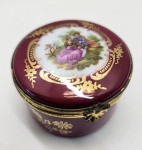 Delicada caixa de porcelana Limoges Castel France, em tom bordô profundo com riquíssima decoração em ouro aplicado à mão e cena galante ao estilo de Fragonard esmaltada no topo. A peça apresenta ferragens em bronze patinado no fecho, mantendo o charme das tradicionais caixas francesas de colecionador. No fundo, traz a marca Limoges Castel France acompanhada da etiqueta H. Stern, confirmando sua procedência refinada e comercialização por uma das joalherias mais prestigiadas. Uma peça de grande apelo decorativo, acabamento impecável e excelente estado de conservação, perfeita para colecionadores de porcelanas francesas de luxo. Dimensões: 3x5 centímetros.