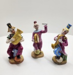 Conjunto de três figuras em porcelana Capo di monte, executadas à mão na Itália, cada uma representando um palhaço músico em trajes vibrantes. As peças exibem modelagem elaborada, pintura policromada típica da manufatura napolitana e expressão caricatural refinada. Cada figura traz marca Capo di Monte / Napoli sob a base. Dimensões:18x9 centímetros cada.