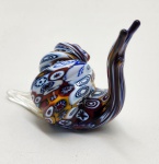 Caracol em vidro artístico Murano trabalhado na técnica tradicional millefiori, evidenciado por sua concha formada por mosaicos multicoloridos em padrões circulares e espiralados. O corpo em vidro translúcido com leve aplicação de pó de ouro complementa a peça, realçando o contraste com a concha elaborada. Escultura inteiramente modelada à mão, apresentando forma fluida, acabamento polido e etiqueta de origem italiana na base. Peça decorativa de excelente presença e forte apelo colecionável, representativa do artesanato vítreo de Murano. Dimensões: 7x8x4 centímetros.