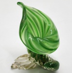 Escultura decorativa em vidro artístico Murano, trabalhada no tradicional vetro soffiato com tonalidade verde esmeralda e detalhes em avventurina dourada. A peça apresenta forma orgânica sinuosa, lembrando folha/trom Beta floral, sustentada por base modelada à mão com aplicações translúcidas. Trabalho típico de Murano  Itália. Dimensões: 12x88x9 centímetros.