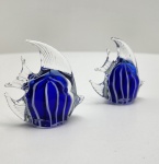 Par de esculturas em vidro artístico Murano, modeladas à mão, apresentando corpo em azul cobalto translúcido com aplicação interna de filetes em branco opalino e nadadeiras em cristal claro trabalhado. Formas harmoniosas, elegantes e bem proporcionadas, evidenciando a técnica tradicional veneziana com belo jogo de transparências e cor saturada. Peças de presença decorativa, acabamento refinado. Dimensões: 8x8x3 centímetros cada.