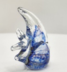 Elegante escultura de peixe em vidro artístico Murano, modelado à mão em massa vítrea translúcida com inclusões marmorizadas em azul profundo, branco e nuances violáceas. A peça apresenta corpo arredondado de grande movimento visual, barbatanas altas em vidro cristalino e base totalmente lisa, típica do acabamento manual veneziano. A transparência envolve delicadas bolhas aprisionadas e veios ondulados que conferem efeito aquático natural e sofisticado. Trabalho de bancada, executado em técnica sommerso com mesclas internas, oferecendo excelente presença decorativa. Dimensões: 10x9x5 centímetros.