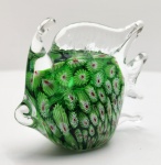 Escultura em vidro artístico de Murano, trabalhada na tradicional técnica millefiori, apresentando corpo densamente preenchido por padrões florais verdes com centros rubros, envolvidos por delicada camada de vidro cristal modelada à mão. A peça exibe a típica composição orgânica muranesca, com nadadeiras e cauda fluidamente estendidas, revelando excelente plasticidade e luminosidade interna. Trabalho de ateliê italiano, séc. XX, de presença decorativa marcante e execução refinada. Dimensões: 10x12x5 centímetros.