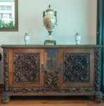 Bufê / Aparador barroco ibérico, Portugal ou Espanha, século XIX. Magnífico bufê em madeira maciça, ricamente entalhado ao modo barroco, com painéis frontais em volutas profundas, acantos vigorosos e ornatos florais esculpidos em alto-relevo. A saia inferior e os montantes seguem a mesma linguagem escultórica, culminando em pés zoomórficos talhados, típicos da tradição ibérica. Ferragens originais em ferro forjado, com fechadura central de desenho arcaizante. Peça de grande presença, representativa do mobiliário de aparato espanhol, preservando pátina antiga e entalhe de excepcional qualidade artesanal. Dimensões:0,80x1,47x0,54 metros.