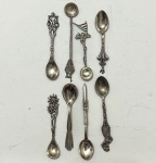 Lote composto por 8 colheres em prata de lei, reunindo modelos decorativos de diversas origens. As peças apresentam cabos trabalhados, terminais figurativos variados e conchas lisas ou ornamentadas, incluindo motivos florais, regionais e tradicionais.34 gramas.