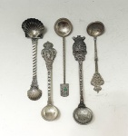 Lote composto por 5 colheres decorativas em prata de lei, de origens diversas e modelos ornamentais. Apresentam cabos trabalhados, terminais figurativos e conchas lisas ou gravadas, com motivos típicos e detalhamento artesanal.120 gramas.