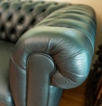 Elegante sofá Chesterfield de três lugares, revestido integralmente em couro natural preto de alta qualidade. Apresenta o tradicional estofamento capitonado profundo no encosto e braços, com botões revestidos e acabamento artesanal característico do modelo clássico inglês. Braços em rolo (scroll arms) na mesma altura do encosto, conferindo equilíbrio visual e imponência à peça. Assentos em três almofadas soltas, amplas e confortáveis, igualmente em couro natural. Estrutura robusta, com pés discretos em madeira. Estado geral muito bom, com desgaste mínimo compatível ao uso, preservando brilho, maciez e integridade do couro. Peça de presença marcante, ideal para ambientes sofisticados como biblioteca, escritório, sala de estar ou home lounge. Dimensões: 0,72x2,10x0,76.