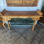 Aparador em madeira maciça, de linhas retas com extremidades superiores em rolos curvos, lembrando perfis de pergaminho enrolado ou beiral de arquitetura oriental. A peça apresenta tampo liso de bela pátina natural e estrutura reforçada por elementos decorativos em volutas laterais. A construção é artesanal, com leve entalhe nos detalhes curvos e proporções elegantes. Dimensões: 0,92x1,50x0,44 centímetros.