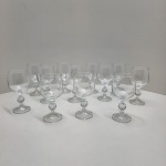 Conjunto composto por 12 taças para vinho branco em cristal transparente, todas com corpo liso e haste ornamentada por esfera facetada, detalhe clássico de lapidação decorativa. Base com leve faceteamento radial, produzindo discreto brilho sob a luz. Dimensões:15x7centímetros.