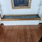 Elegante vitrine horizontal expositora, elaborada com moldura em madeira entalhada e acabamento em douração, destacando ornatos em relevo de inspiração clássica. A peça apresenta tampo frontal envidraçado, permitindo visualização integral do conteúdo interno, ideal para exposição de miniaturas, coleções de colheres decorativas ou pequenos objetos de interesse histórico.Internamente, conta com painel de fundo escuro que acentua o contraste das peças expostas. O fechamento frontal possui fecho metálico decorativo, preservando a estética tradicional. Dimensões:0,12x2,20x0,50. ( os itens que estão dentro da vitrina não acompanha).