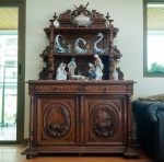 Imponente aparador europeu em carvalho maciço, ricamente entalhado, composto por corpo inferior com portas duplas e alçado superior sustentado por colunetas torneadas. As portas apresentam entalhes em alto-relevo de temática cinegética, representando animais selvagens em meio a folhagens  motivo tradicional das grandes oficinas de marcenaria do norte da França e Bélgica no final do século XIX.O alçado superior exibe prateleiras com laterais ornadas por volutas, arabescos e elementos vegetais, além de coroamento elaborado com cartelas e figuras zoomórficas. Todo o conjunto é executado com extraordinária precisão, demonstrando domínio técnico no talho da madeira e forte influência do repertório neorrenascentista.O móvel possui exemplar correlato no acervo do Museu do Prado, Madrid, pertencente a um conjunto de mobiliário de tradição centro-europeia, reforçando a relevância tipológica e historicista da peça.