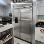 Refrigerador de alto padrão GE Monogram, modelo side-by-side, concebido para instalação embutida e acabamento integrado à arquitetura da cozinha. Estrutura integral em aço inox escovado, com portas amplas, puxadores tubulares verticais e painel superior com grelha de ventilação característica da linha profissional. Possui dispenser frontal embutido para água e gelo, além de sistema de refrigeração de alta capacidade, ideal para ambientes gourmet.