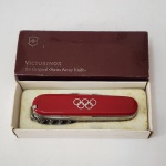 Victorinox  Edição Olímpica, década de 1970/80. Modelo clássico em cachos vermelhos, ostentando os anéis olímpicos gravados na face principal. Peça original suíça, acompanhada de caixa de época, extremamente bem preservada. Exemplar colecionável, representativo das séries comemorativas produzidas pela Victorinox para eventos internacionais.