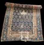 Raro tapete persa Karabagh, originário da região do Cáucaso Meridional, conhecido por suas composições gráficas e padrões repetitivos inspirados em motivos tribais. A peça apresenta um campo decorado por módulos geométricos em repetição, emoldurados por uma borda de inspiração caucasiana com motivos angulares em tons de azul petróleo, terracota, bege e marfim. Tecida à mão em lã sobre urdume de algodão, a obra demonstra características tradicionais dos Karabagh mais antigos: paleta profunda, desenhos densamente distribuídos e estrutura firme. A peça apresenta desgaste acentuado ao centro e nas extremidades, com áreas de perda de nós visíveis, especialmente na parte inferior, onde o urdume está exposto. As bordas apresentam fragilidade e perda parcial. Dimensões:2,46x0,88