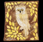 Tapeçaria brasileira assinada Luiz Adolpho, execução artesanal em lã sobre base têxtil, representando uma coruja.A obra apresenta composição figurativa com coruja central em destaque, modelada em pontos altos e baixos que conferem volume ao corpo da ave e expressividade ao olhar. O fundo, trabalhado em tons terrosos, é decorado por folhas estilizadas em amarelo e ocre, criando moldura orgânica ao redor da figura principal. A paleta quente enfatiza a leitura decorativa e o caráter artesanal da peça.No verso, inscrição manuscrita com nome do artista, reforçando procedência e autenticidade.Trabalho representativo do artesanato têxtil figurativo brasileiro da segunda metade do século XX. Dimensões: 60x50 centímetros.