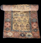 Tapete caucasiano Mesquim (Meshkin), execução manual em lã sobre lã, no formato runner.A peça apresenta campo central estreito em tom ocre-amarelado, ornado por sequência vertical de ramos florais estilizados, característicos da produção tribal da região. As largas faixas laterais exibem medalhões geométricos florais em azul, verde, terracota e marfim, criando contraste cromático marcante e reforçando a estética típica dos teares caucasianos. A cercadura múltipla, formada por frisos geométricos em azul e marrom, enquadra o conjunto com equilíbrio e ritmo visual.Exemplar de forte identidade etnográfica, com desgaste compatível à idade, preservando ainda a integridade decorativa e o desenho tradicional caucasiano. Apresenta desgaste natural do tempo.  Dimensões: 3,28x0,82 centímetros. 