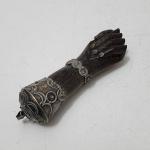 Figa amuleto em jacarandá e prata de lei, joia de crioula, expressão da cultura afro-brasileira.Amuleto tradicional de proteção, esculpido em jacarandá maciço no formato de mão fechada, símbolo amplamente associado às práticas apotropaicas de matriz africana no Brasil. A peça recebe ornamentos em prata de lei cinzelada, formando pulseira e terminações decorativas em motivos circulares e geométricos, característicos das chamadas joias de crioula, utilizadas por mulheres negras e afrodescendentes nos séculos XVIII e XIX como marcadores de identidade, devoção e status.A patina antiga sobre madeira e metal reforça a autenticidade do exemplar, que representa de modo significativo o encontro entre tradições africanas e a ourivesaria luso-brasileira.Peça de alto interesse etnográfico, colecionável e histórica dentro do repertório da cultura afro no Brasil. Dimensões: 17 centímetros.