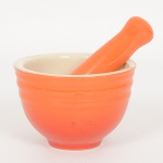 PORCELANA, conjunto com dois (2) itens: 1 cadinho e 1 soquete, tonalidade laranja, marca EG (Edu Guedes),medindo a maior peça 13,5 cm comprimento, sinais de uso, vide foto.