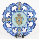 FAIANÇA PORTUGUESA, um (1) prato decorativo com ornamentação policromada, predominância da tonalidadeazul, representando Brasão de Armas Português, borda vazada e ornada em elementos vegetalistas, possui váriosquebrados, colados e perdas, origem ALCOBAÇA, medindo 20 cm diâmetro, sinais de uso, vide foto.
