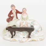 PORCELANA, uma (1) escultura representando dama tocando piano ao lado de cavaleiro, policromada, arremates aouro, marca SANTANA (Pedreira, SP, fundada em 1941 por Joaquim Carlos e Flamínio Maurício Netto; em 1943entraram os sócios Adelino dos Santos Gouveia e Horácio Lopes; em 1966 comprou do grupo Nadir Figueiredo asinstalações da antiga Santa Rita, onde fundou a Porcelana Veracruz, que passou a produzir louça doméstica e a Santanapassou a produzir apenas isoladores elétricos; em 2000 ocorre a integração de ambas e passam a produzir somenteisoladores), medindo 9,5 x 11,5 x 6,5 cm, ideal para coleção de bibelôs, vide foto.