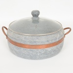 EQUIPAMENTO DE COZINHA, uma (1) panela, confeccionada em soapstone (pedra sabão), torneada, cinta e alçaem metal cobreado, com tampa em vidro incolor e translúcido com pega da tampa em pedra torneada, marca BRASART, medindo 29 cm diâmetro.