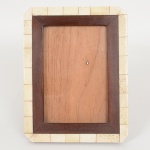 FOTOGRAFIA, um (1) porta-retratos retangular com quinas chanfradas, confeccionado em madeira, recoberto complacas em osso ou marfim, envidraçado, possui haste expositora no verso, medindo 21 x 16 cm, sinais de uso, vide foto.