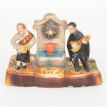 FAIANÇA PORTUGUESA, uma (1) escultura policromada representando tocador de alaúde e senhora ladeandouma fonte, medindo 12,5 x 4,5 x 9 cm, ideal para coleção de cristaleira, sem marca de manufatura aparente, vide foto.