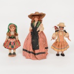 BRINQUEDOS, três (3) bonecas distintas com cabeças e membros em polímero, vestes em tecido, todas com trajestípicos, uma delas de Portugal, medindo a maior 33 cm, sinais de uso, vide foto.
