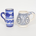 PORCELANA E FAIANÇA, duas (2) canecas distintas: 1 com propaganda da Churrascaria Gaúcha, Rio de janeiro,manufatura CORCOVADO, Pedreira, SP; 1 com ornamentação pintada a mão na técnica blue and white, manufaturanão identificada na base, medindo a maior 11 cm altura, sinais de uso, vide foto.