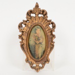 QUADRO, uma (1) miniatura oval em tecido estampado policromado, representando menino com cachorro no colo,moldura em estuque, vazada e com douração, medindo 21 x 11,5 cm, vide foto.