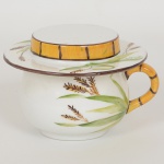 PORCELANA, uma (1) caneca com tampa no formato de chapéu, pintada a mão em policromia por Atelier,representando elementos vegetalistas, datada 99, sinais de uso, vide foto.