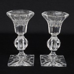 CRISTAL, par (2) castiçais, incolores e translúcidos, moldados em caneluras, base trapezoidal, fuste em gomos,bobeche octogonal, medindo 13 cm altura, vide foto.