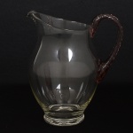 CRISTAL, uma (1) jarra bojuda incolor, alça na tonalidade roxa em torçaide, translúcida, procedênciaChecoslováquia, medindo 20 cm altura, sinais de uso, vide foto.