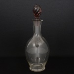 CRISTAL, uma (1) licoreira bojuda incolor, tampa na tonalidade roxa em torçaide, translúcida, procedênciaChecoslováquia, medindo 30 cm altura, não aparenta ter sido usada ou pouco uso, vide foto.