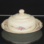 PORCELANA POLONESA, uma (1) manteigueira com tampa, ornamentação floral policromada, arremates comfrisos a ouro, manufatura KPM (Krister Porzellan-Manufaktur 1831 a 1920, fundada no ano de 1831 por Carl FranzKrister; em 1867 foi premiado na Exposição Internacional de Paris mesmo ano da sua morte; em 1920 mudou a razãosocial para Krister Porzellan-Manufaktur AG 1920 a 1952; em 1921 foi autorizado pelo governo a produzir moeda deporcelana (Notgeld); em 1945 depois da Segunda Guerra Mundial o território deixou de ser alemão e passou a integrar aPolônia; em 1952 foi nacionalizada e passou a ser Fabryka Porcelany Krzysztof 1952 a 1995; em 1995 mudou a razãosocial para Fabryka Porcelany Krzysztof SA, funciona até a atualidade), medindo 18,5 cm diâmetro, sinais de uso, videfoto.