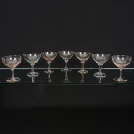 VIDRO, sete (7) taças para champanhe ou espumante, incolores e translúcidas, bojo com singela lapidaçãovegetalista, fuste cilíndrico, base em bolacha, medindo 11 cm altura, sinais de uso, vide foto.