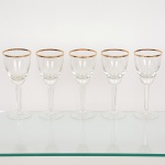 CRISTAL, cinco (5) taças para vinho, incolores e translúcidas, fuste hexagonal, base em bolacha, borda comarremate a ouro, medindo 19 cm altura, sinais de uso, vide foto.