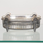 METAL PRATEADO, uma (1) fruteira oval tipo jardineira, borda vazada, ornamentação relevada em colunas,perolados e elementos vegetalistas, manufatura WMF (Württembergische Metallwaren Fabrik, fundada em 1853 emGeislingen, como Metall-Waren-Fabrik Straub & Schweizer, em 1862 foi medalha de ouro na Exposição Mundial emLondres, a partir de 1880 mudou a razão social para o nome atual), marcas auxiliares: I/O (garantia de uma grama deprata depositada por decímetro quadrado); B (confeccionado em pewter ou antimônio); OX (oxidado com sulfa epotássio com acabamento em polimento), recipiente interno em vidro, incolor e translúcido, quebrado e colado, medindo23 x 13 cm, sinais de uso, vide foto.