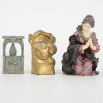 ESCULTURAS, três (3) distintas: 1 representando figura feminina em posição de oração, confeccionada em resinapolicromada, medindo 7 cm altura; 1 representando BUDDHA (popularmente conhecido como SIDDHARTHAGAUTAMA, foi um príncipe de uma região no sul do atual Nepal que, tendo renunciado ao trono, se dedicou à busca daerradicação das causas do sofrimento humano e de todos os seres, e desta forma encontrou um caminho até ao despertarou iluminação), confeccionada em metal prateado azinhavrado, medindo 4,5 cm altura; 1 representando cabeça feminina(possivelmente uma tampa), confeccionada em metal dourado, medindo 5 cm altura, vide foto.